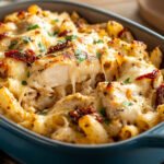 Creamy chicken pasta baked in a rustic blue casserole dish, topped with golden melted cheese and sun-dried tomatoes, garnished with fresh herbs – featured blog image of the Marry Me Chicken Pasta recipe.