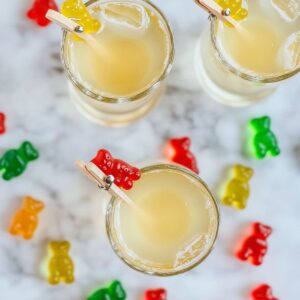 Overhead view of gummy bear shots with red and yellow bears clipped to the rims on a marble surface