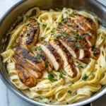 Blackened chicken Alfredo with creamy fettuccine in a skillet, garnished with parsley
