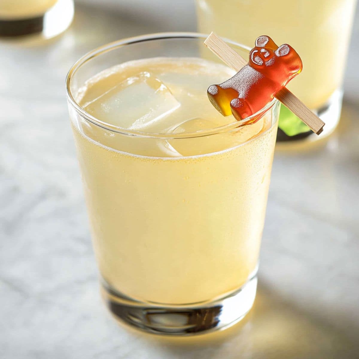 Chilled gummy bear cocktail with clipped candy garnish on marble surface