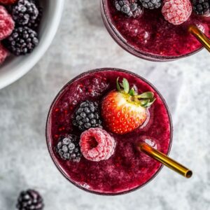 Frozen berry slushies garnished with fruit and gold straws