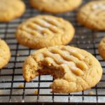 Peanut butter cookie with a bite taken out, cooling on wire rack with sugar topping.