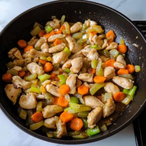 Sautéed chicken with carrots, celery, and onions in a skillet for the base of Bisquick chicken and dumplings.
