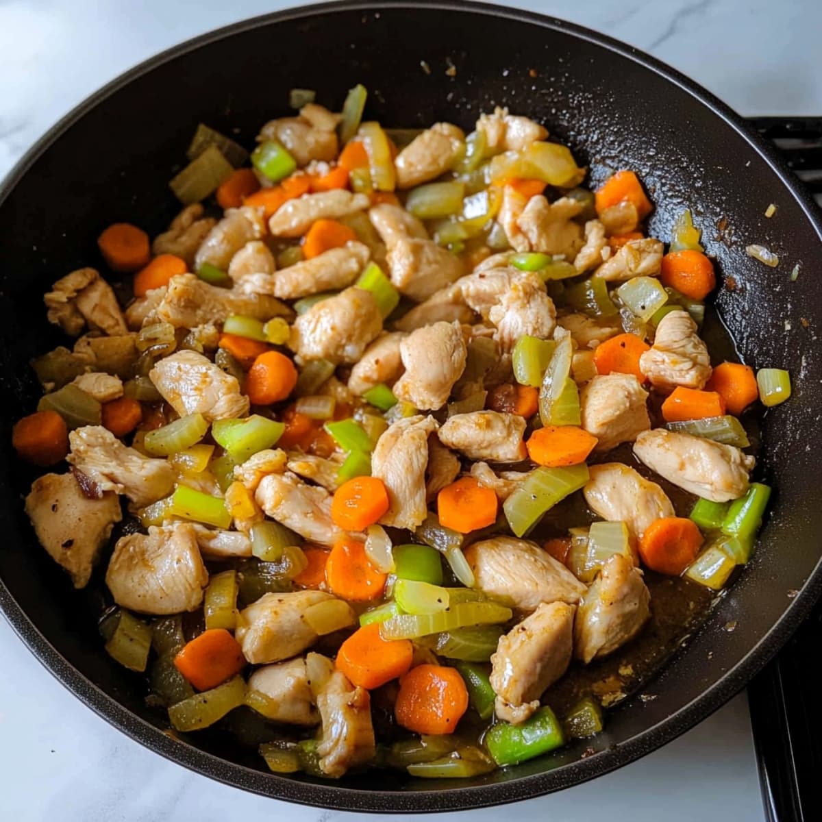 Sautéed chicken with carrots, celery, and onions in a skillet for the base of Bisquick chicken and dumplings.