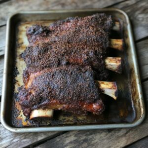 Smoked beef back ribs resting on a tray with peppery bark