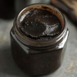 Open jar filled with glossy dark vanilla bean paste from a homemade vanilla paste recipe