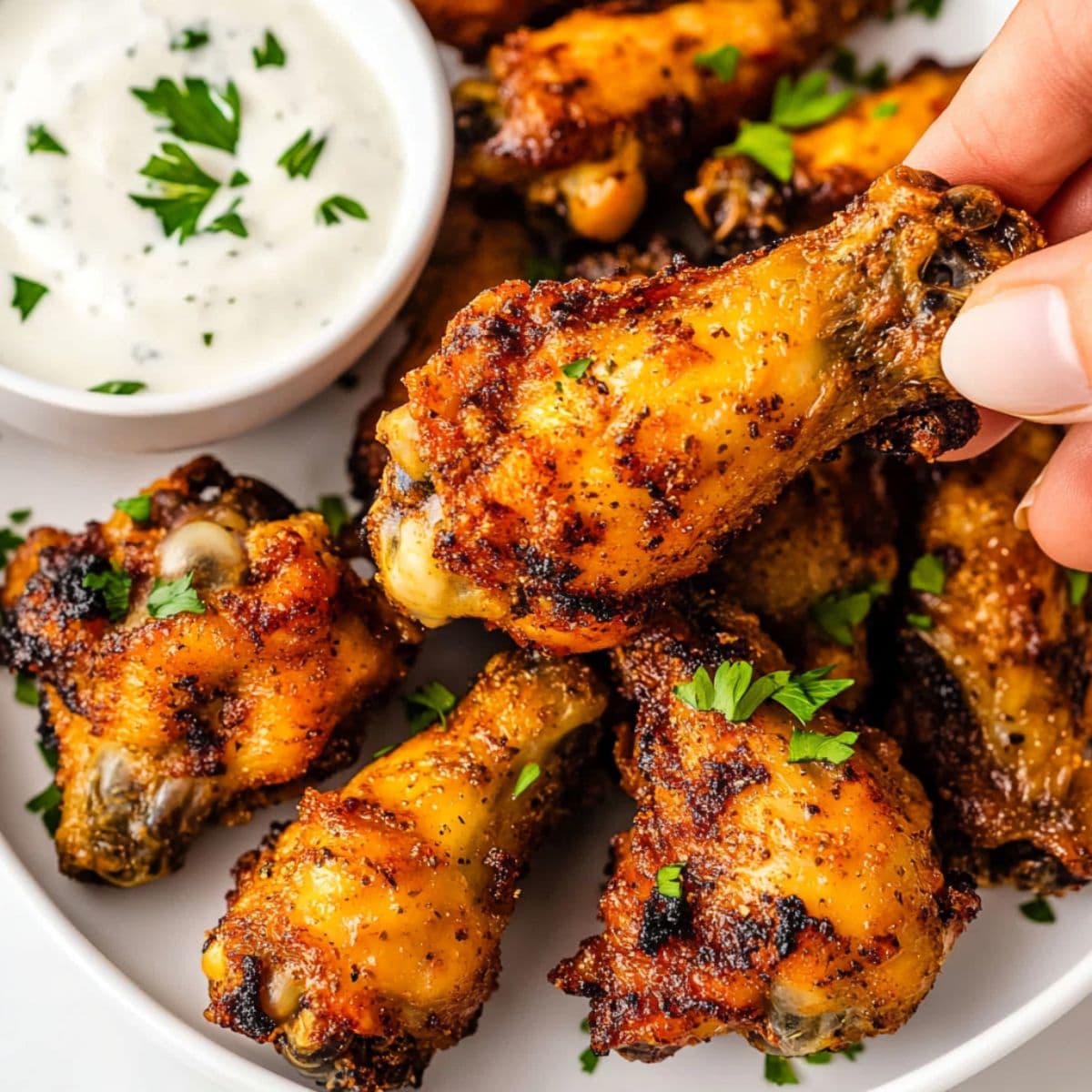 Ultimate air fryer chicken wings with perfect golden brown crispy skin being held showing incredible seasoning and ranch dipping sauce on white plate