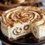 Cinnamon roll cheesecake sliced showing internal swirl layers with graham cracker crust and cream cheese filling with cinnamon patterns