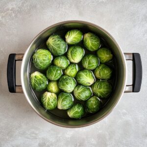 Fresh bright green Brussels sprouts in stainless steel pot with water, ready for blanching in Longhorn steakhouse copycat recipe preparation