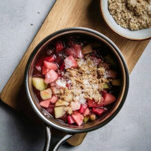 A bowl of simmered rhubarb and apple filling in a vibrant red sauce, ready for rhubarb crisp.