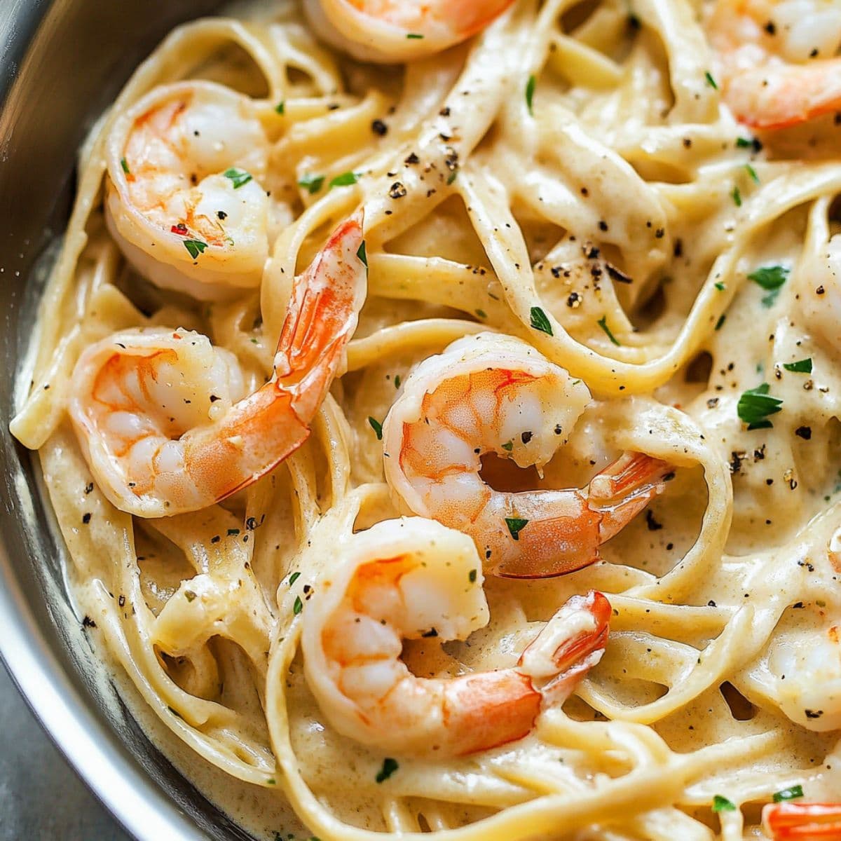 Shrimp Pasta Recipes. Close-up of creamy shrimp pasta with linguine and black pepper in a stainless steel pan.