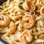 Shrimp Pasta Recipes. Close-up of creamy shrimp pasta with linguine, garnished with parsley and black pepper.