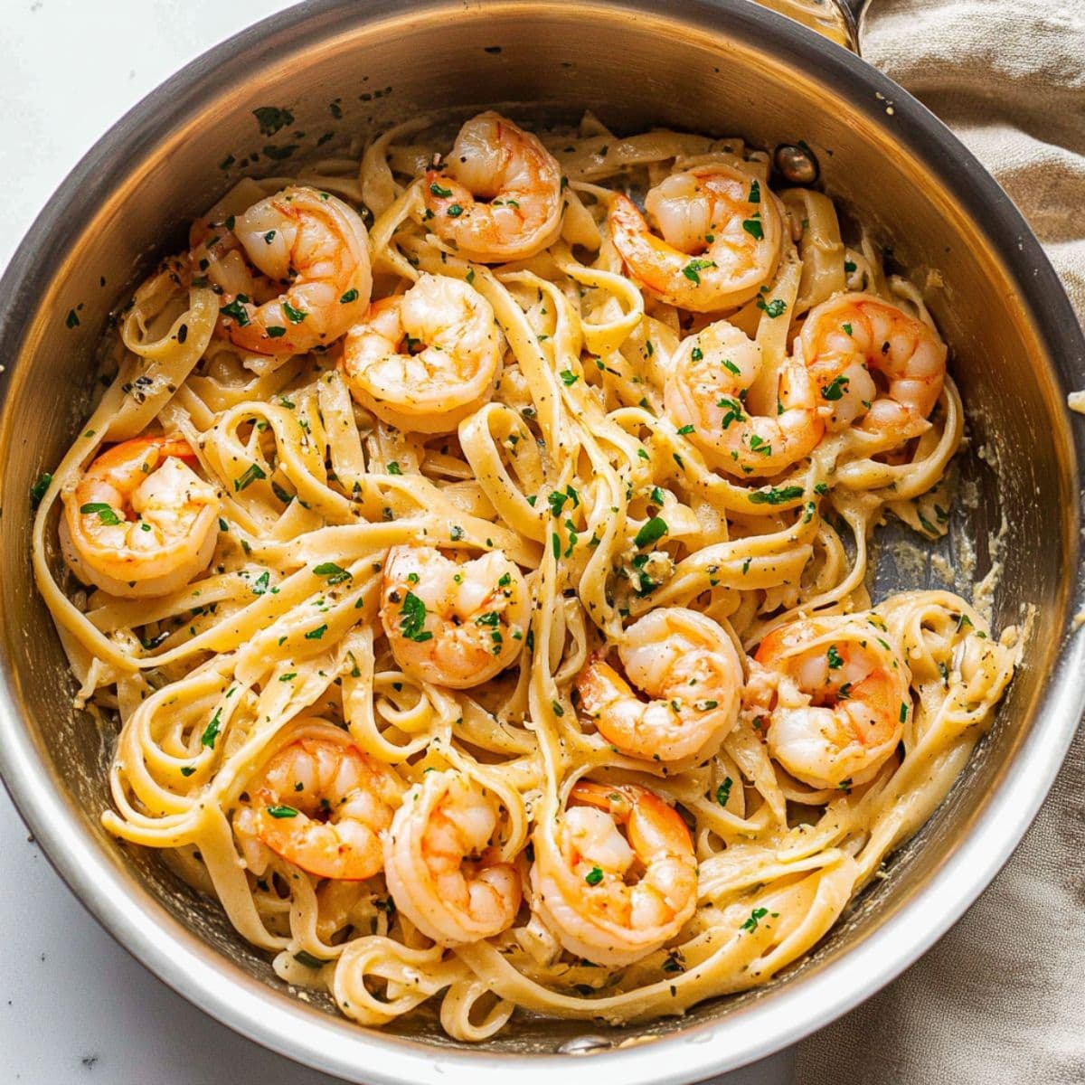 Shrimp linguine pasta in a creamy garlic sauce with chopped parsley, presented with a personal creative touch.