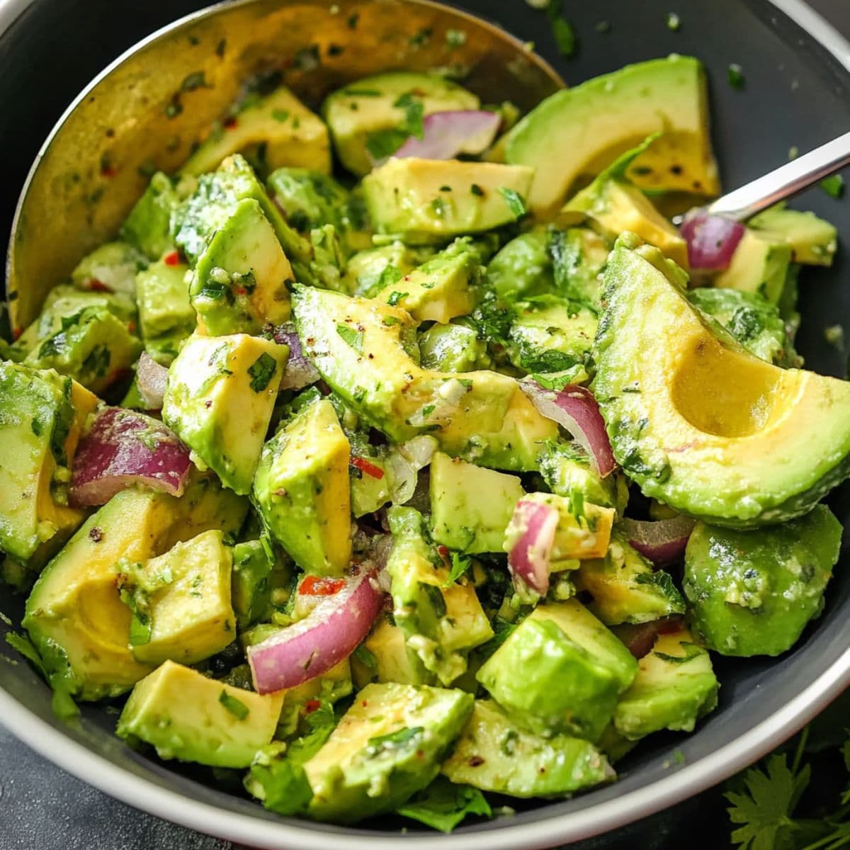 Avocado cucumber salad in mixing bowl with serving spoon, ready to pair with main dishes