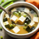 Miso soup traditional Japanese recipe with tofu cubes wakame seaweed and scallions in spoon