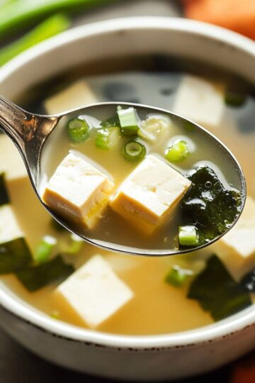 Miso soup traditional Japanese recipe with tofu cubes wakame seaweed and scallions in spoon
