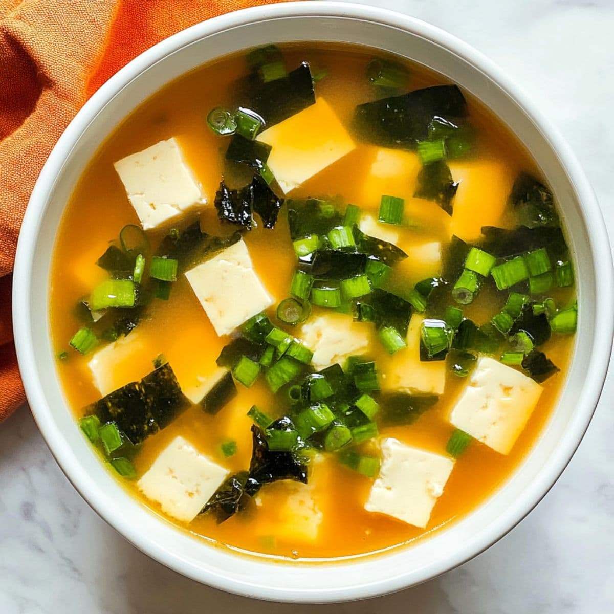 Miso soup authentic homemade recipe in white bowl with tofu wakame and green scallions