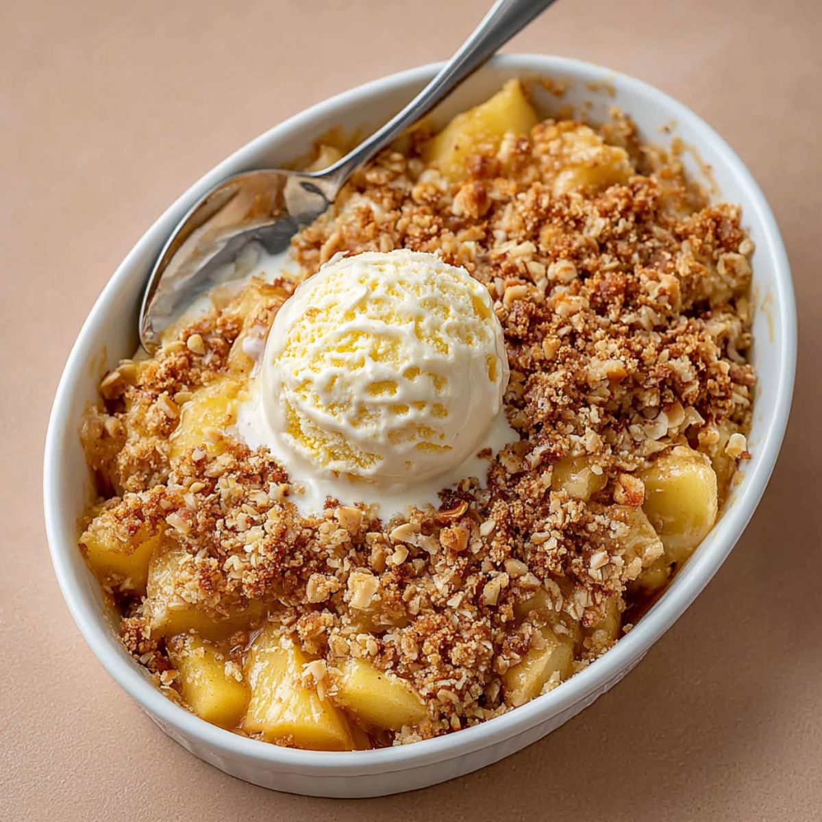 Apple crisp recipe served in white bowl with vanilla ice cream and golden oat crumble topping, showing tender baked apples underneath