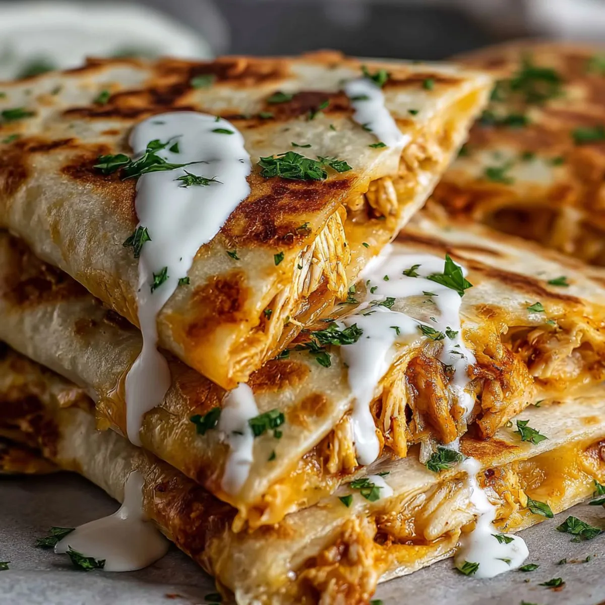 Chicken quesadilla recipe showing golden crispy tortillas with melted cheese oozing out, topped with sour cream and fresh cilantro