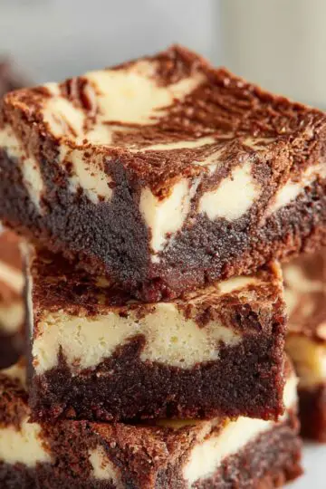 Cream cheese brownies stacked showing fudgy chocolate base with creamy swirled cheesecake layers, homemade marble brownie recipe