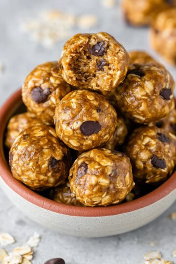 Energy bites recipe showing golden brown no-bake balls with oats, chocolate chips in ceramic bowl on marble surface