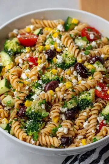 A close-up shot of a high-protein pasta salad filled with chicken, vegetables, and creamy dressing on a white plate.