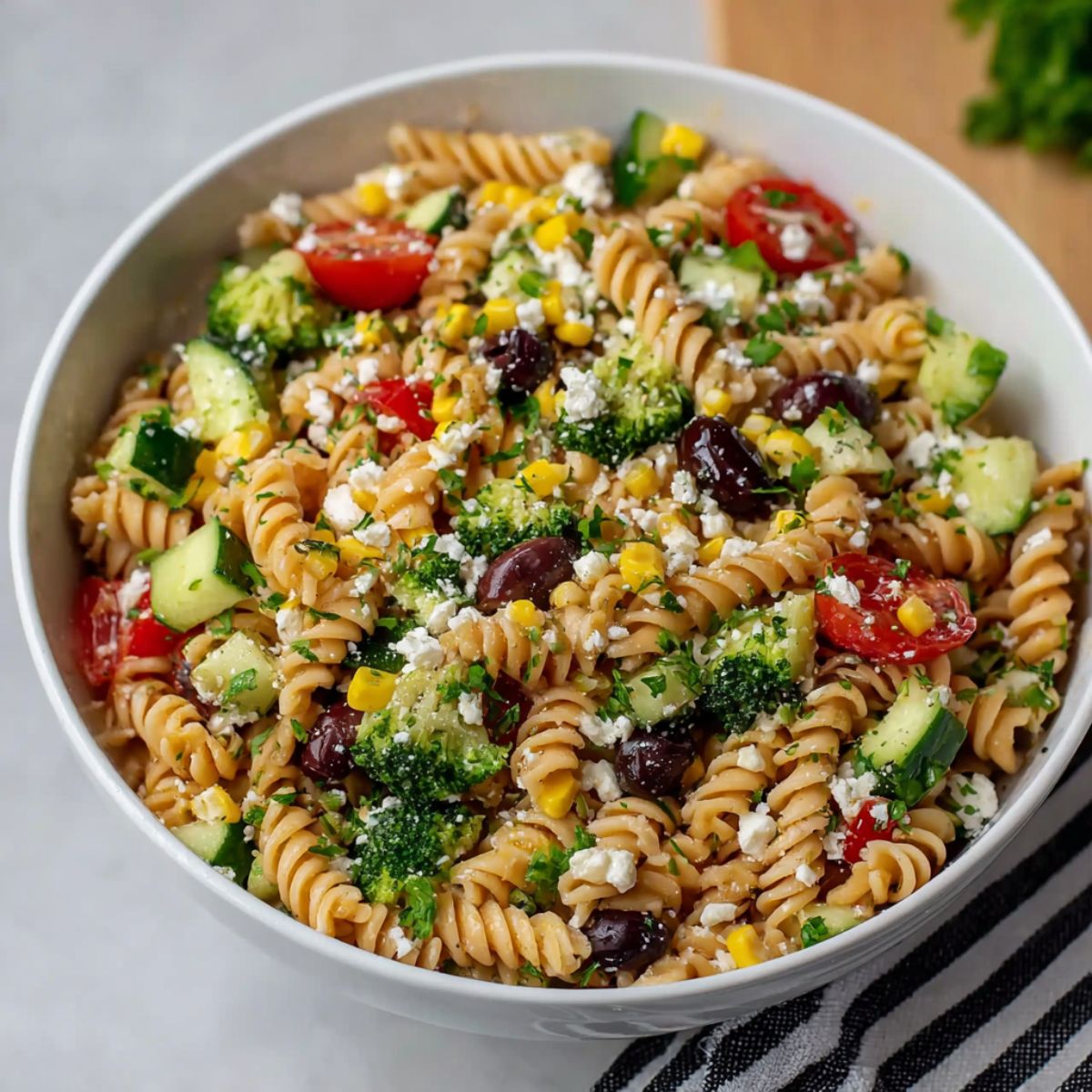 A close-up shot of a high-protein pasta salad filled with chicken, vegetables, and creamy dressing on a white plate.