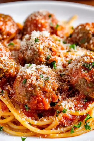 Spaghetti and meatballs with rich tomato sauce and fresh Parmesan cheese on white plate, homemade Italian pasta recipe