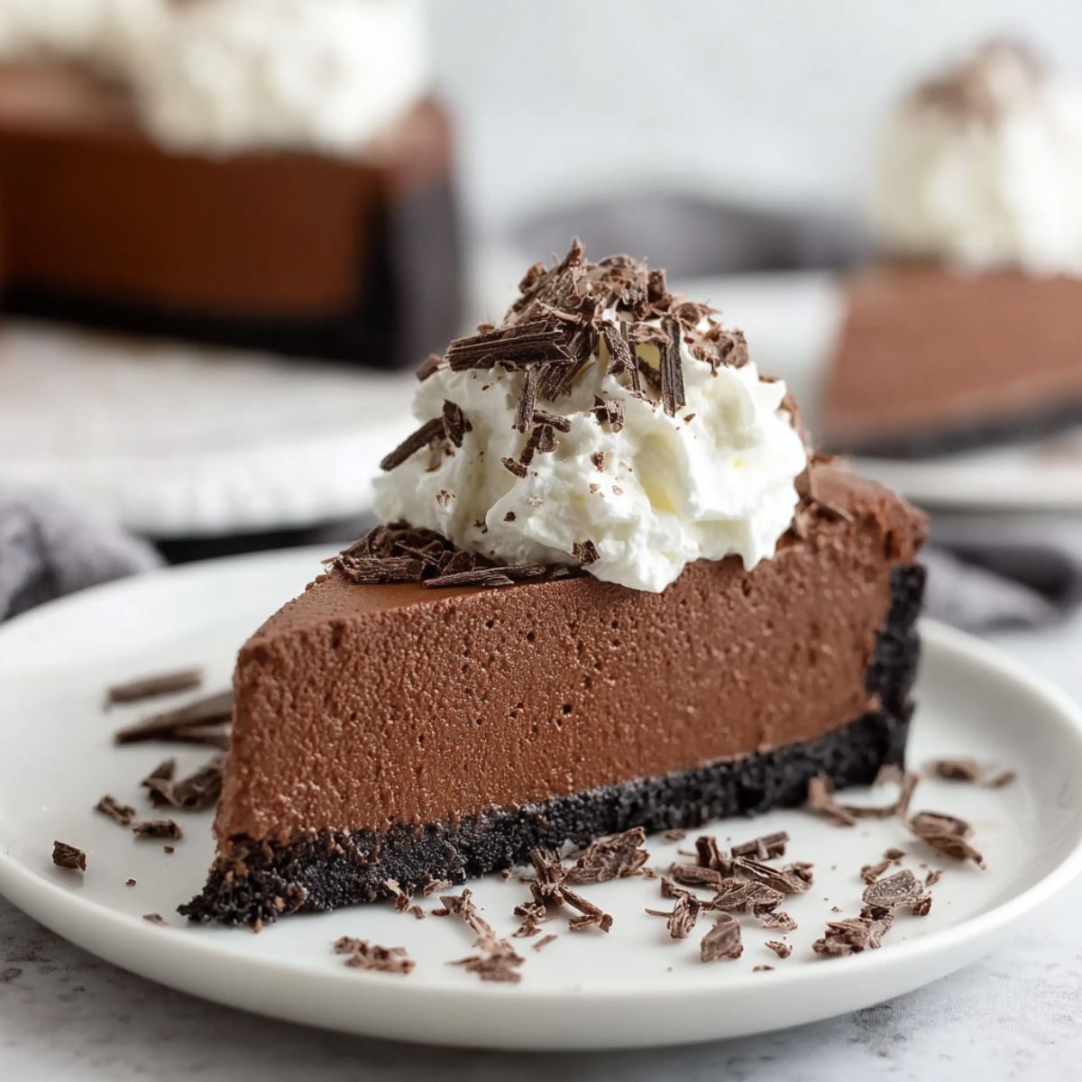 Baileys cheesecake slice showing smooth Irish cream filling on chocolate cookie crust with whipped cream and chocolate shavings on white plate