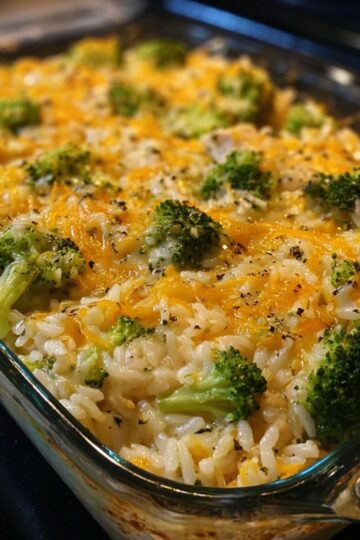 Chicken broccoli rice cheese casserole close up view showing golden melted cheese with fresh broccoli florets and seasoned rice in glass dish