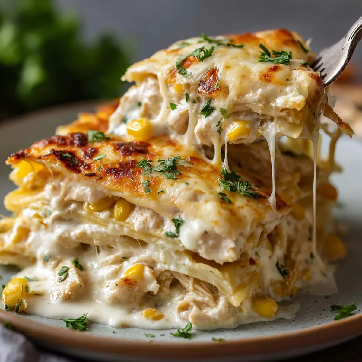 Enchilada casserole layered Mexican dish with melted cheese stretching from fork, showing corn, herbs, and golden bubbly top