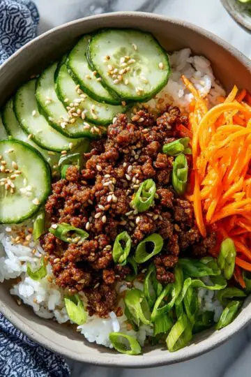 Korean beef bowl, with ground beef, rice, and fresh vegetables in a bowl.