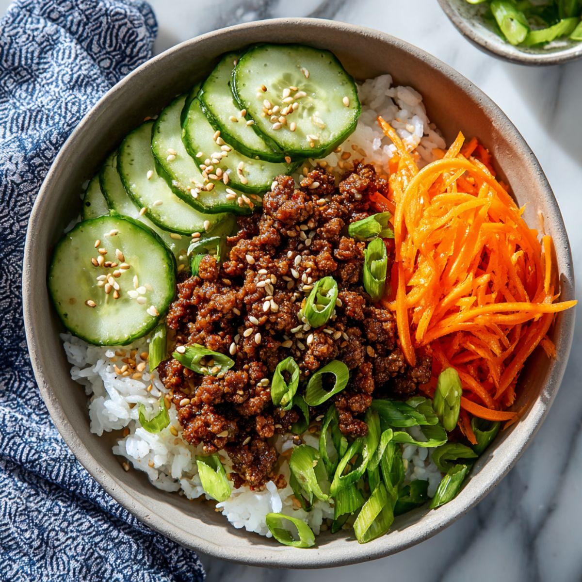 Korean beef bowl, with ground beef, rice, and fresh vegetables in a bowl.