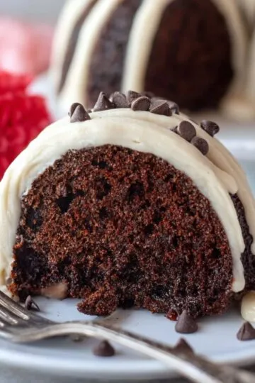 Fork next to a slice of chocolate chip Bundt cake topped with white icing.