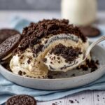 oreo dirt cake recipe showing creamy layered dessert with crushed Oreos scooped from a glass pan