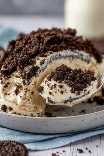 oreo dirt cake recipe showing creamy layered dessert with crushed Oreos scooped from a glass pan