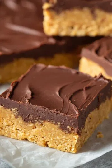 Protein bars with chocolate topping and peanut butter oat base on parchment paper showing chewy homemade texture