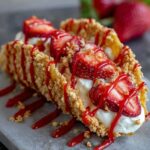 Easy Strawberry Crunch Cheesecake Tacos - Crispy taco shells filled with cheesecake, topped with fresh strawberries and a crunchy golden topping.