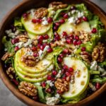 Winter salad in wooden bowl with sliced pears, pomegranate seeds, candied walnuts, goat cheese crumbles, mixed greens, festive holiday side dish