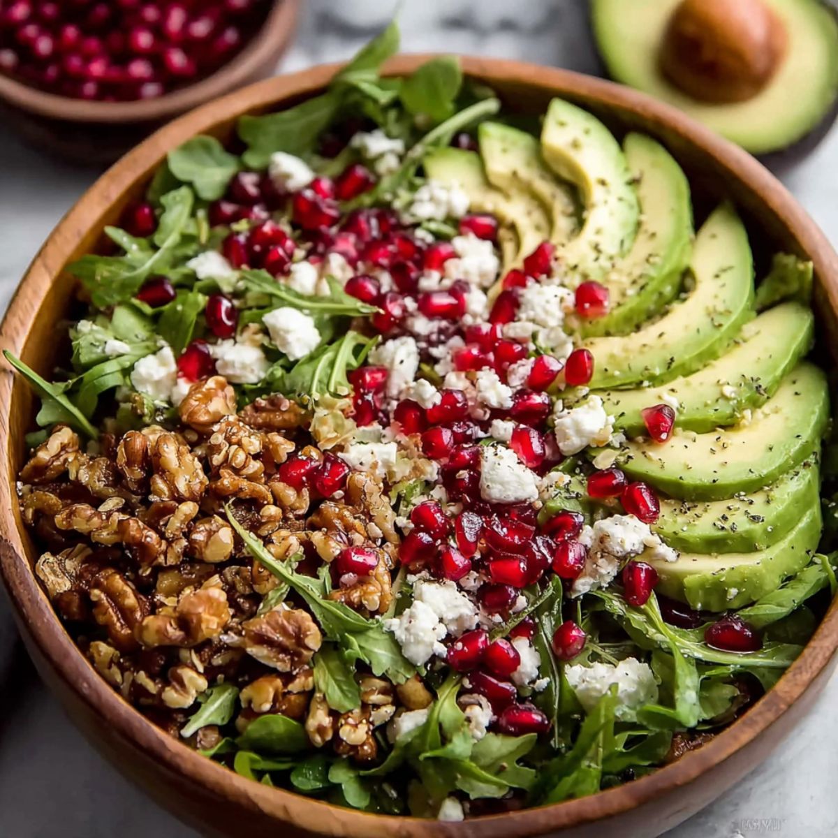 Winter salad recipe with avocado, pomegranate, walnuts, goat cheese, arugula, organized in sections, healthy colorful bowl salad