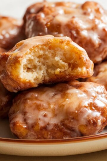 Apple fritter bites showing a soft doughy interior and a shiny translucent glaze