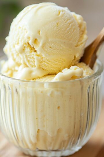Ribbed glass cup holding creamy pineapple dole whip recipe with a wooden spoon.