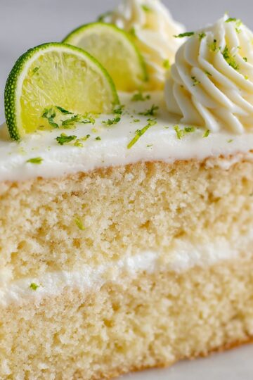 Close-up side view of fluffy key lime cake layers with smooth white frosting.