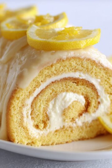 Close-up of a lemon cream swiss roll topped with fresh lemon slices.