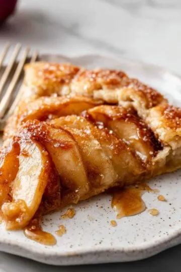 Close up slice of French Apple Tart with sticky syrup and flaky crust