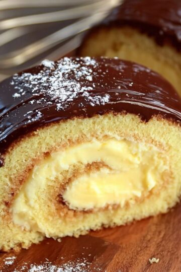 Boston Cream Roll Cake 6 A thick slice of Boston Cream Roll Cake showing soft sponge and creamy custard.