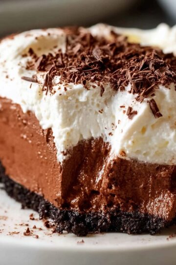 Single slice of Chocolate Creme Pie with airy whipped topping and fine chocolate shavings.