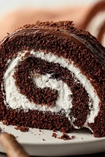Sliced chocolate Swiss roll showing porous cake sponge and smooth white cream spiral