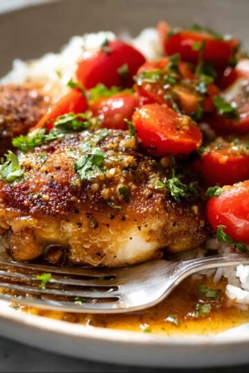 Garlic Butter Chicken Thighs 1 Warm Garlic Butter Chicken Thighs served over white rice with cherry tomatoes.