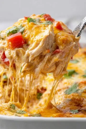 Cheesy King Ranch Chicken Casserole lifted with a metal spoon showing gooey texture